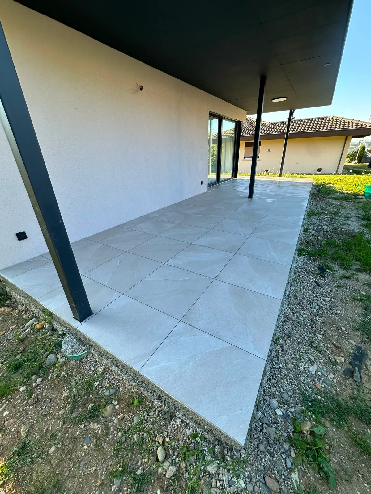 Gedeckter Sitzplatz: Terrassenplatten in Steinoptik unter einem gedeckten Sitzplatz